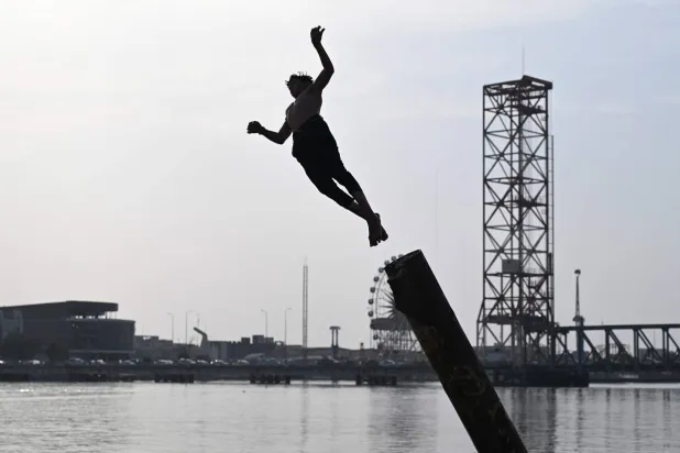 شاب يغوص في شط العرب المائي هرباً من الحر في البصرة جنوب العراق (أ.ب)