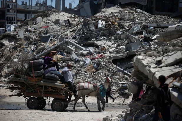 فلسطينيون وسط أنقاض المنازل المدمَّرة بمخيم جباليا للاجئين في شمال قطاع غزة (رويترز)