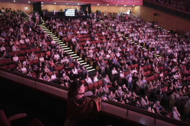 امرأة تشاهد الجلسة الافتتاحية لفعالية قمة السلام الشعبية في القدس يوم الجمعة (أ.ب)