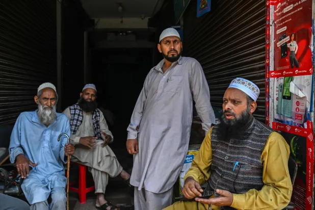 ملاك متاجر يجلسون قرب محطة حافلات في بلدة بونش بمنطقة جامو الهندية (أ.ف.ب)