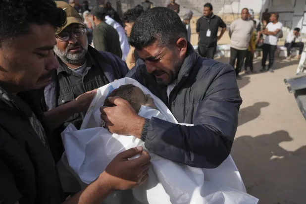 الفلسطيني محمد الأغا يحمل طفلته زينة (عامان) بعد مقتلها إثر غارات إسرائيلية في مستشفى «ناصر» بخان يونس في قطاع غزة (أ.ب)