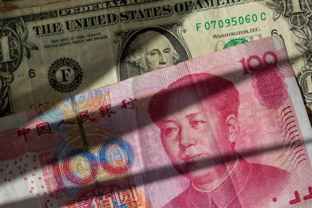 أوراق نقدية صينية باليوان بين عدة أوراق نقدية من الدولار الأميركي (د.ب.أ)