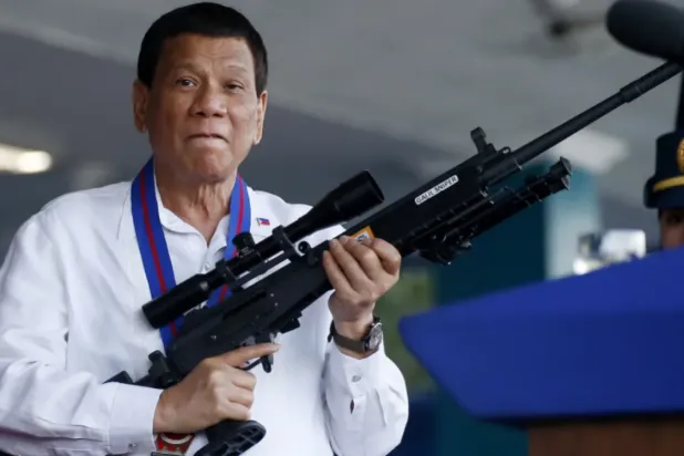 Eski Filipin lideri Rodrigo Duterte, 2018 yılında Manila'nın kuzeydoğusundaki bir polis karakolunu ziyareti sırasında elinde makineli tüfek tutuyor. (AP)