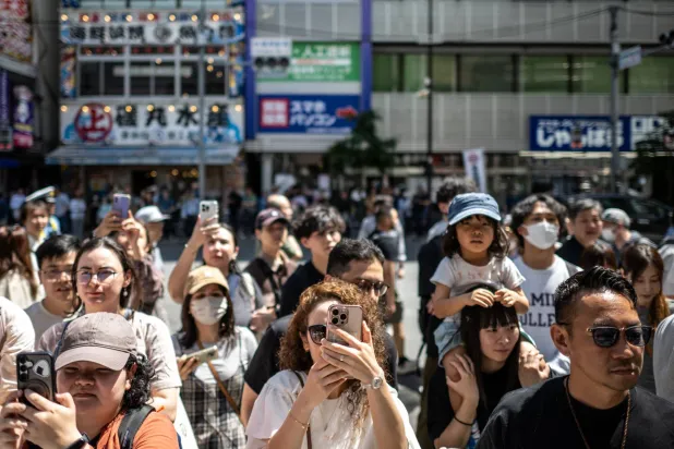 مشاهدون يلتقطون صوراً خلال أحد الاحتفالات الشعبية وسط العاصمة اليابانية طوكيو (أ.ف.ب)