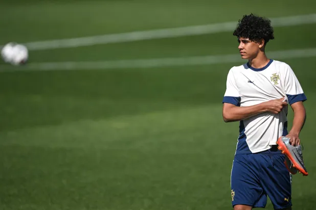 جونيور مرتدياً القميص الرسمي للمنتخب وممسكاً به بفخر (أ.ف.ب)