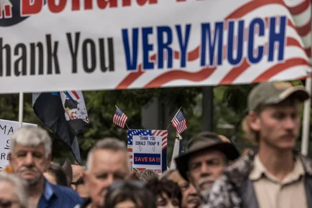 مجموعة من المتظاهرين البيض يرفعون لافتات شكر لترمب لمنحهم اللجوء إلى أميركا (أ.ف.ب)