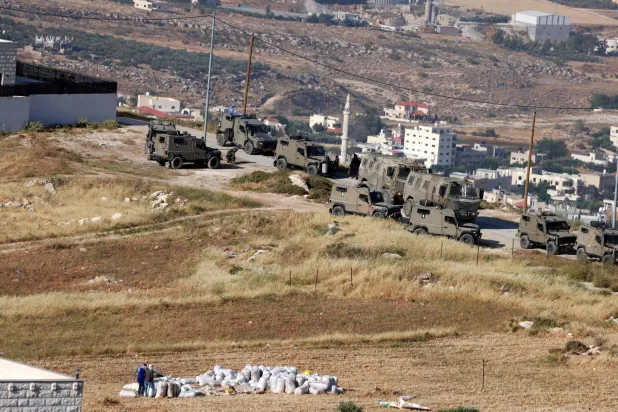 المركبات العسكرية الإسرائيلية تتخذ مواقعها خلال غارة للجيش في الضاحية الشرقية لمدينة نابلس بالضفة الغربية المحتلة (أ.ف.ب)