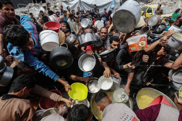 فلسطينيون يصطفون في طابور طويل للحصول على حصة طعام من مطبخ خيري في بيت لاهيا شمال قطاع غزة (د.ب.أ)