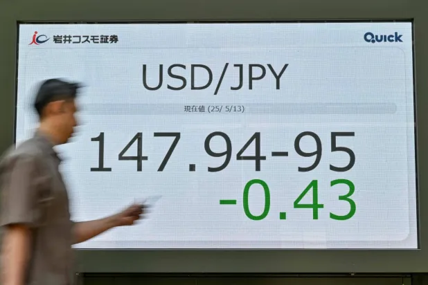 رجل يمر أمام شاشة تعرض حركة الين مقابل الدولار وسط العاصمة اليابانية طوكيو (أ.ف.ب)