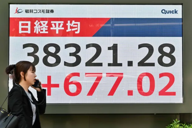 سيدة تمر أمام لوحة إلكترونية تعرض حركة الأسهم في وسط العاصمة اليابانية طوكيو (أ.ف.ب)