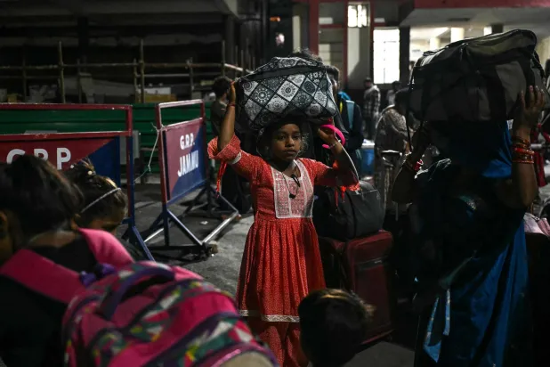 نازحون يحملون أمتعتهم قبل صعودهم على متن قطار في محطة سكة حديد في جامو (أ.ف.ب)