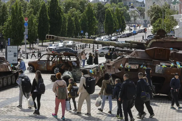 أوكرانيون يتفرجون على معدات عسكرية روسية مدمرة في كييف الأحد (إ.ب.أ)