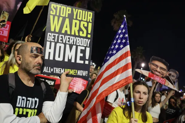 Relatives and supporters of Israelis held hostage in Gaza since the October 7 attacks by Palestinian militants, lift placards and national flags calling on the US to intervene for their release, in front of the US embassy branch office in Tel Aviv, on May 13, 2025, during the visit to Israel of US Special Envoy to the Middle East Steve Witkoff. (Photo by Jack GUEZ / AFP)