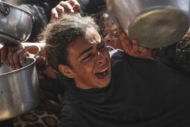 طفلة فلسطينية تعاني من أجل الحصول على طعام من مطبخ خيري في خان يونس بقطاع غزة (أ.ب)