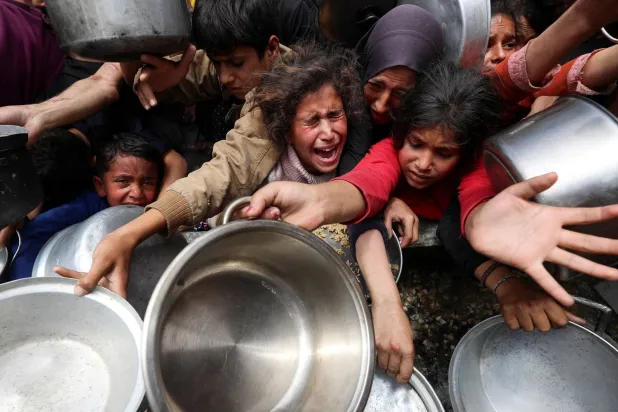 فلسطينيون ينتظرون الحصول على طعام من مطبخ خيري في جباليا (رويترز)