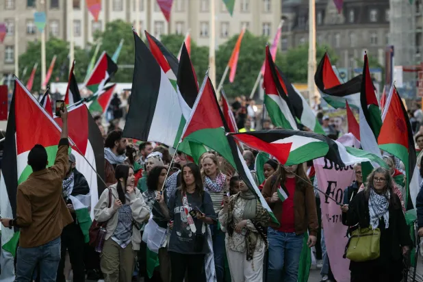 متظاهرون يحملون أعلاماً فلسطينية خلال مسيرة صامتة في بازل احتجاجاً على مشاركة إسرائيل في مسابقة يوروفيجين (أ.ف.ب)