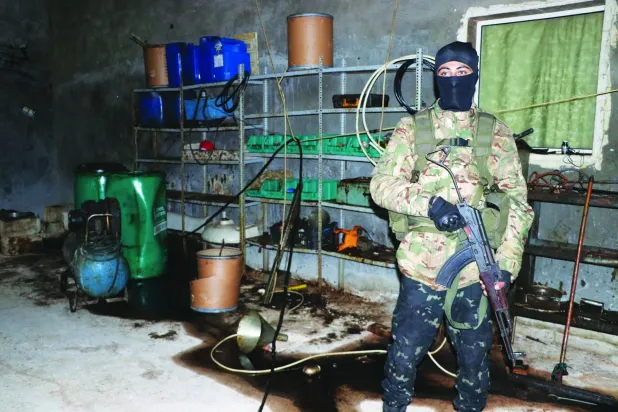 عنصر أمن سوري يقف أمام معمل لصناعة حبوب الكبتاغون صادرها الأمن السوري خلال حملة تمشيط (الشرق الأوسط)