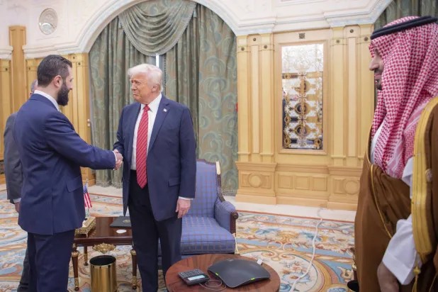 In this photo released by the Saudi Royal Palace, Syria's interim President Ahmad al-Sharaa, left, shakes hands with President Donald Trump, center, in Riyadh, Saudi Arabia, Wednesday, May 14, 2025. At right is Saudi Crown Prince Mohammed bin Salman.(Bandar Aljaloud/Saudi Royal Palace via AP)