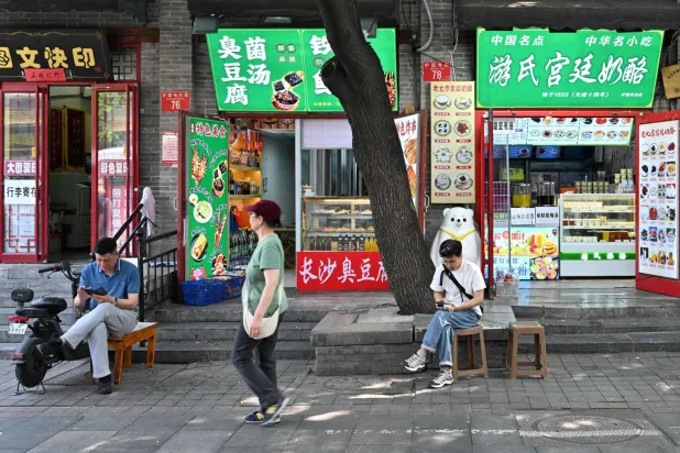 مشاة في أحد الشوارع التجارية بوسط بكين (أ.ف.ب)