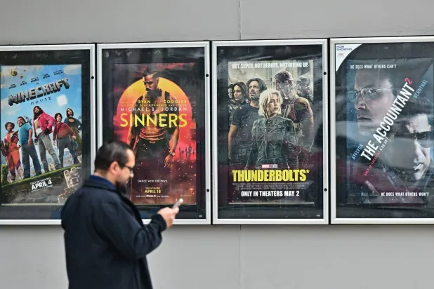 رجل يمر أمام ملصقات لأفلام تُعرض في صالة سينما بمونتيبيللو في كاليفورنيا (أ.ف.ب)