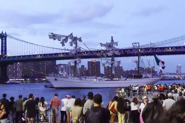 ينظر الناس إلى كواوتيموك، وهي سفينة تدريب تابعة للبحرية المكسيكية، وهي راسية في نهر إيست بعد اصطدام السفينة بجسر بروكلين، في مدينة نيويورك (د.ب.أ)