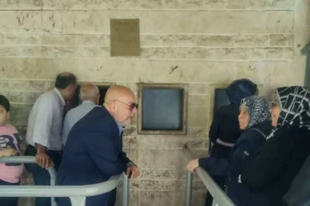 Syrian Minister of Economy and Industry Nidal Al-Shaar standing in line outside Al-Razi Bakery in Aleppo Province, listening to citizens’ concerns (Facebook page). 