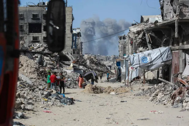 تصاعد الدخان شمالاً بينما كان الفلسطينيون يتنقلون مع متعلقاتهم الشخصية عبر جباليا فراراً من شمال قطاع غزة باتجاه مدينة غزة (أ.ف.ب) 