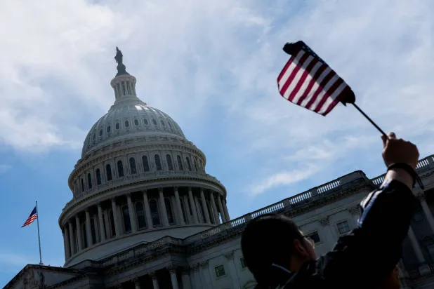 زائر يلوّح بعلم أميركي بالقرب من مبنى الكابيتول (رويترز)