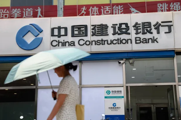 امرأة تمر أمام فرع لأحد المصارف في «الضاحية المالية» بالعاصمة الصينية بكين (إ.ب.أ)