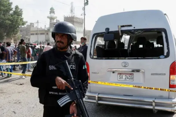 Polis memuru, Pakistan'ın Karaçi kentinde intihar bombası saldırısının olduğu yerde, çitle çevrili hasarlı bir aracın yanında nöbet tutuyor (Arşiv- Reuters)