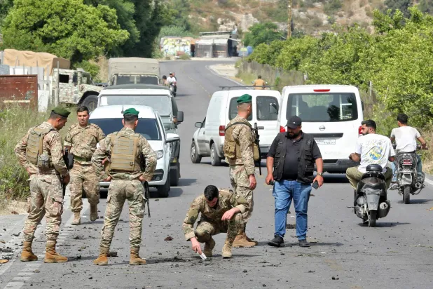 جنود من الجيش اللبناني يتفقدون حفرة بعد غارة جوية إسرائيلية استهدفت سيارة في أبو الأسود في جنوب لبنان (أ.ف.ب)