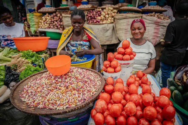 سيدتان تبيعان مجموعة متنوعة من المواد الغذائية بما في ذلك البازلاء والأرز والفاصوليا والطماطم (أ.ف.ب)