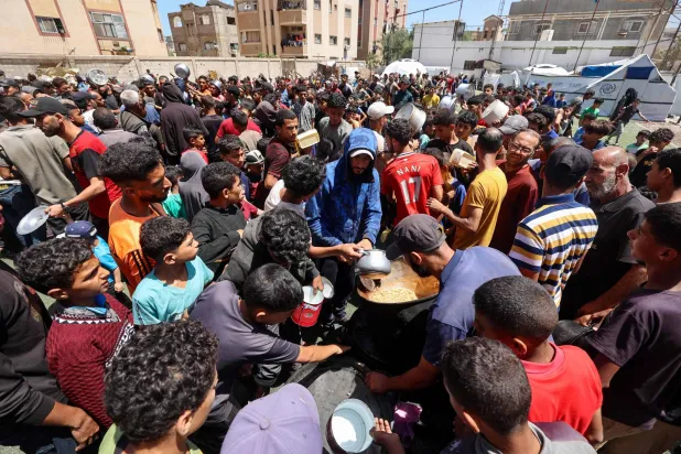 ينتظرون أمام تكية للحصول على طعام في النصيرات بوسط قطاع غزة السبت (أ.ف.ب)