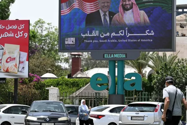 Şam'da Suudi Veliaht Prens Muhammed bin Salman ve ABD Başkanı Donald Trump'ın fotoğraflarının yer aldığı büyük bir pankartın altında şu ifadeler yer alıyor: Yürekten teşekkür ederim (AFP)
