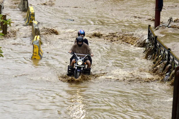 سائق دراجة نارية يخوض في شارع غارق بالمياه بعد هطول أمطار غزيرة في جواهاتي (د.ب.أ)