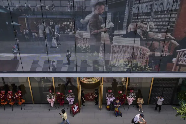 عمال يترقبون الزبائن بأحد المتاجر الكبرى في بكين (أ.ب)