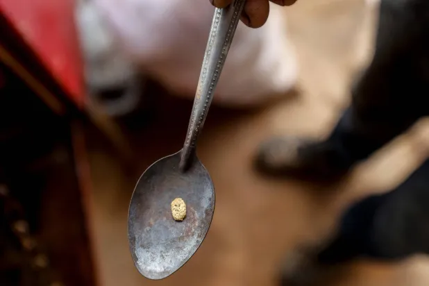 رجل يعرض حجراً ذهبياً صغيراً تم استخراجه من منجم ذهب في مدينة إلدورادو بفنزويلا (أ.ف.ب)