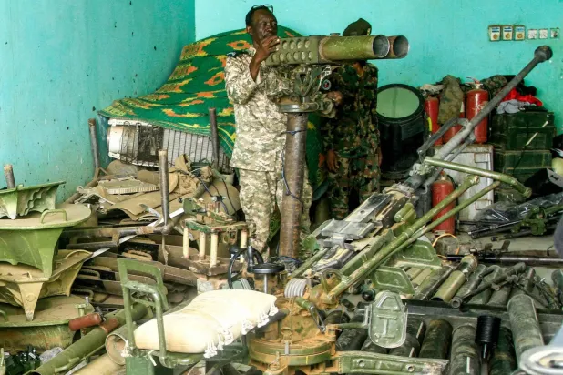Sudanlı bir asker, Omdurman'ın Salha bölgesinde ordu tarafından ele geçirilen askeri teçhizatı gösteriyor (AFP)