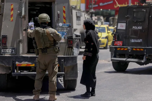 قوة إسرائيلية تعتقل سيّدة تعمل في محل للصيرفة بمدينة الخليل في الضفة الغربية المحتلة (أ.ف.ب)