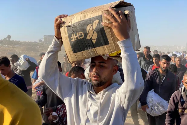 نازحون فلسطينيون يحملون إمدادات إغاثية من «مؤسسة غزة الإنسانية» في جنوب غزة (أ.ف.ب)