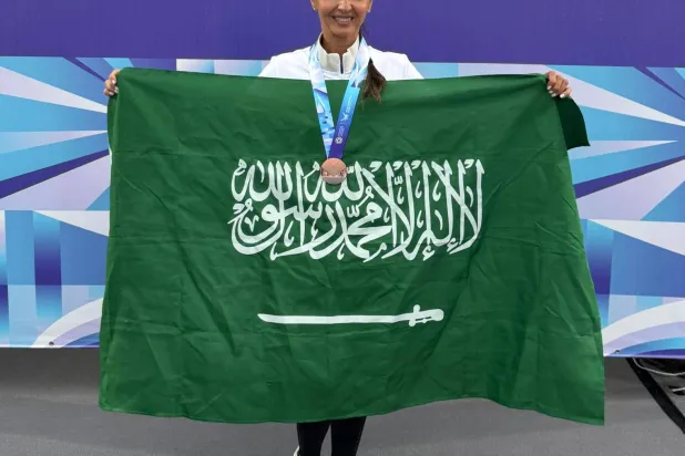 ثريا بن لادن محتفلة بالعلم السعودي عقب تتويجها بالميدالية (الشرق الأوسط)