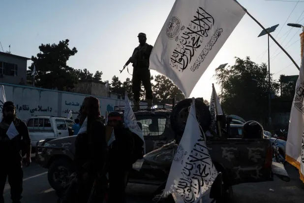 أفراد أمن من «طالبان» يرفعون علم الحركة (غيتي)