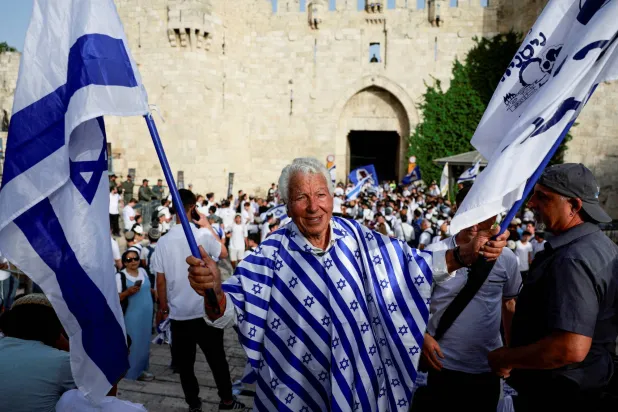 شخص يحمل عَلم إسرائيل أمام باب العامود بالقدس (رويترز)