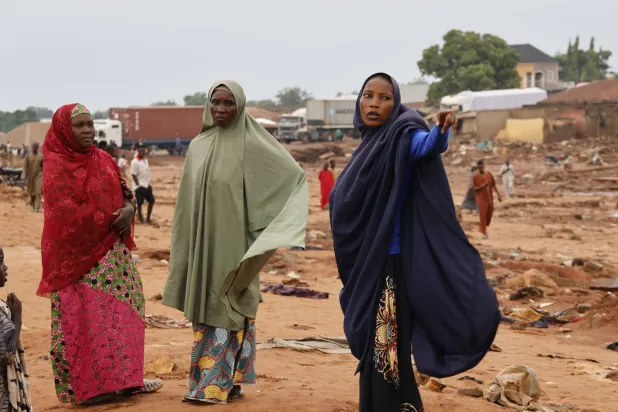 نساء من ضحايا الفيضان الذي اجتاح منزلهن بعد هطول أمطار غزيرة يفحصن الأضرار ببلدة موكوا بولاية النيجر بنيجيريا 1 يونيو 2025 (إ.ب.أ)