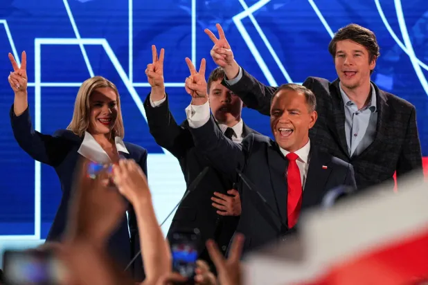 مرشح التيار القومي المعارض كارول نافروتسكي مع زوجته وابنه يرفعون علامة النصر بعد نتائج أولية أظهرت تقدمه مساء الأحد (رويترز)