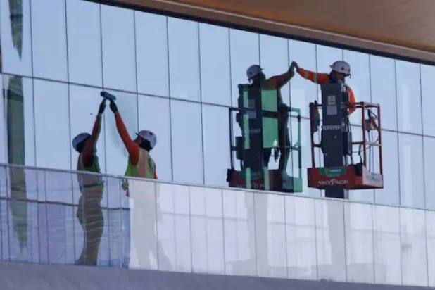 عمال بناء يركّبون نوافذ بمبنى مكاتب شبه مكتمل في سان دييغو بكاليفورنيا (رويترز)