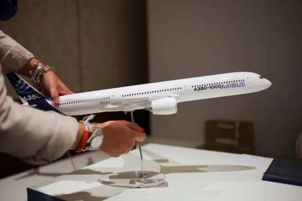 موظف يثبّت نموذجاً لطائرة إيرباص داخل جناح الشركة بمعرض النقل الجوي السنوي بنيودلهي بالهند (رويترز)