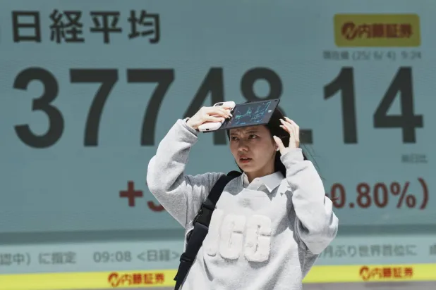 فتاة أمام لوحة إلكترونية تعرض حركة الأسهم وسط العاصمة اليابانية طوكيو (أ.ب)