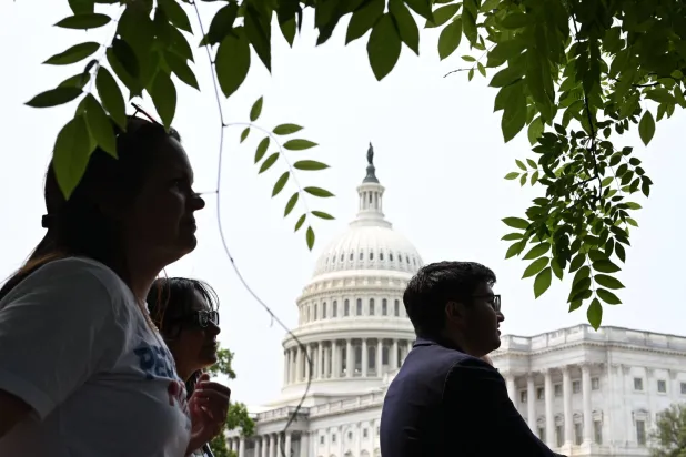 يستمع الناس إلى متظاهرين يتجمعون للتظاهر قبل مؤتمر صحافي لدعوة أعضاء مجلس الشيوخ الجمهوريين للتصويت ضد الموازنة (أ.ف.ب)