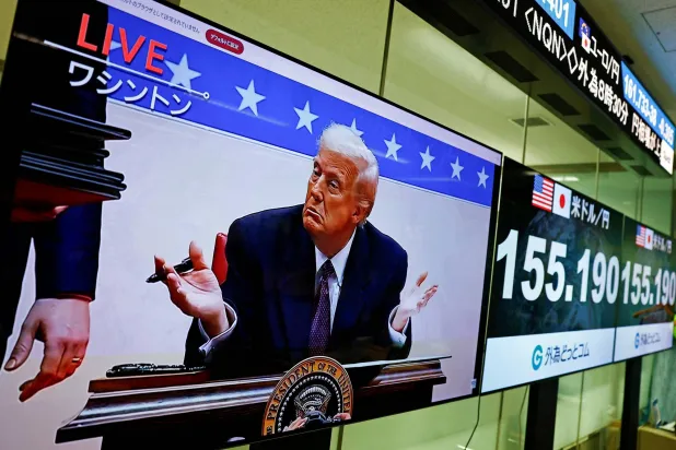 شاشة تبث لقطات حية للرئيس الأميركي دونالد ترمب بجوار شاشات تعرض سعر صرف الين الياباني مقابل الدولار الأميركي في طوكيو (رويترز)